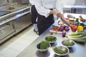 una imagen de un chef cortando verduras en una cocina profesional